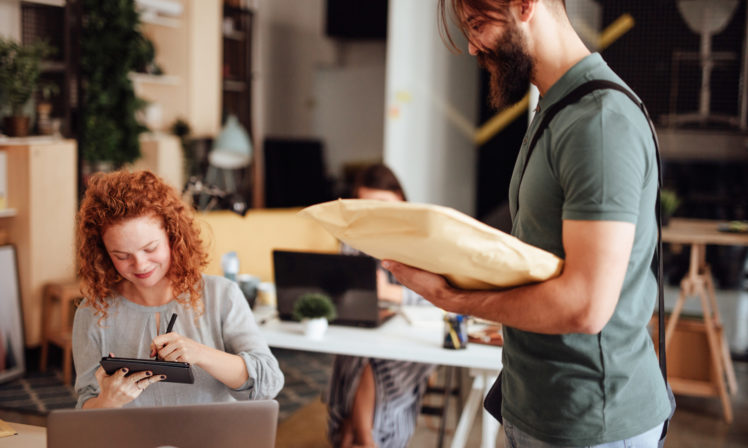 Smiling businesswoman signing for package delivery
